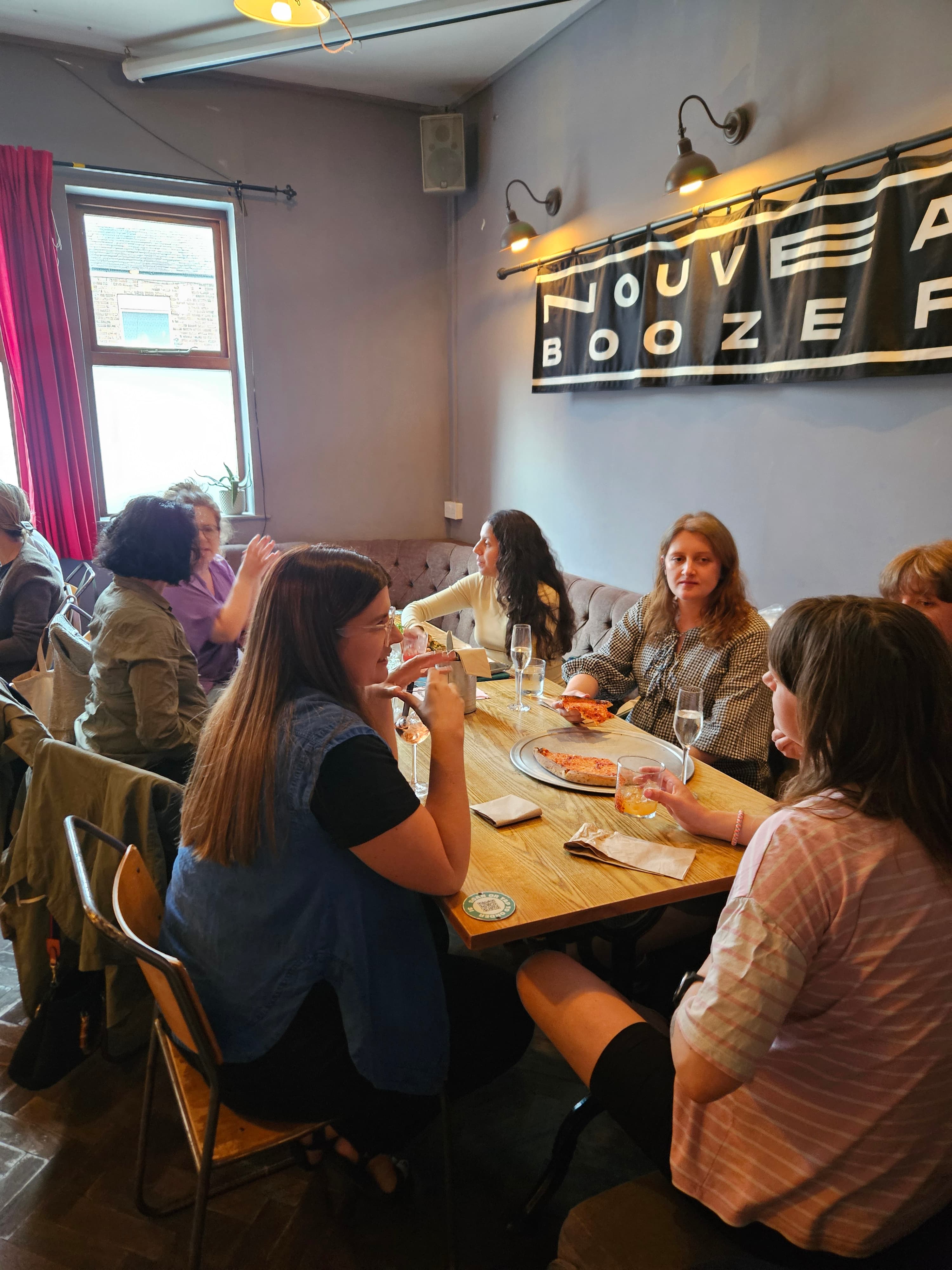Group of pregnant women chatting over pizza and drinks at Bumps at the Beagle in Chorlton